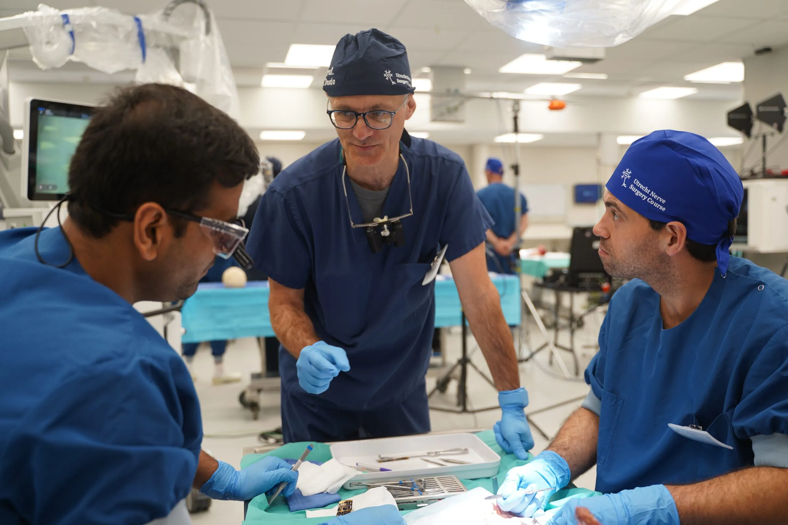 Faculty member guiding two participants at the dissection table
